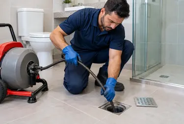 Técnico desentupindo um ralo em Araguari com ferramentas manuais.